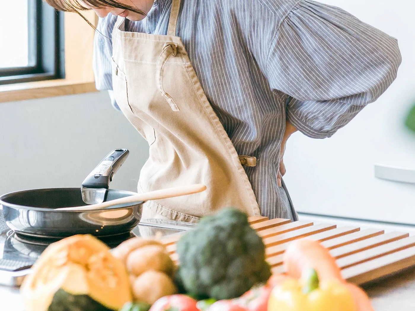 料理中に腰痛に襲われる女性